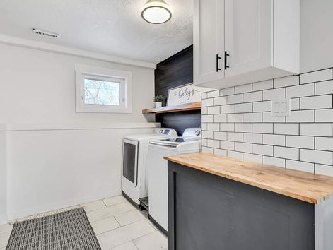 laundry room with subway tile wall, cabinets, black shiplap and washer and dryer