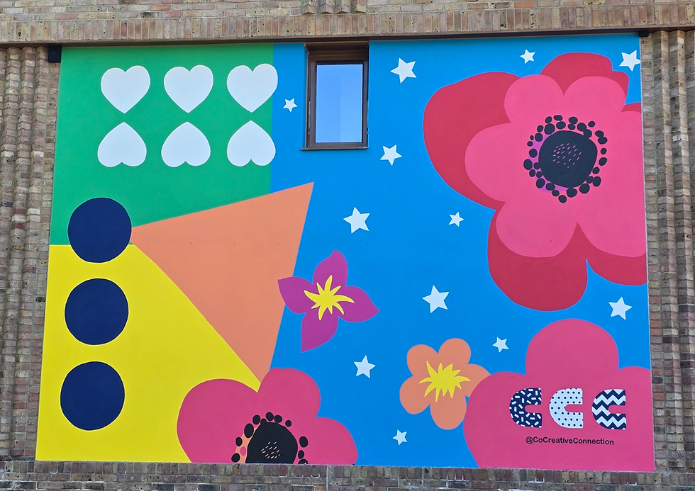 Colourful mural on brick wall with hearts, stars, and flowers in bold colours including orange, green, pink and blue. Includes text on the mural: "@CoCreativeConnection." and CCC's logo. Bright, playful mood.
