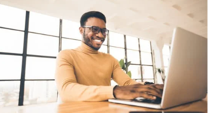 A business professional working on a laptop with a confident smile.