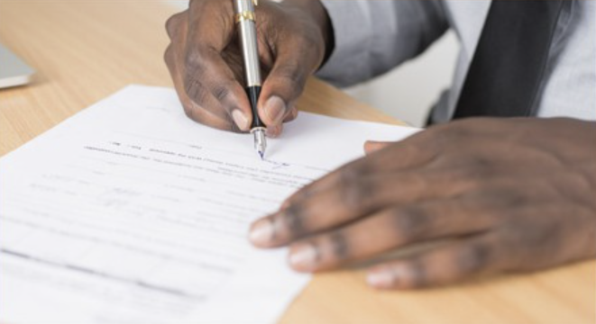 Professional signing a government contract document after completing the proposal and evaluation process.