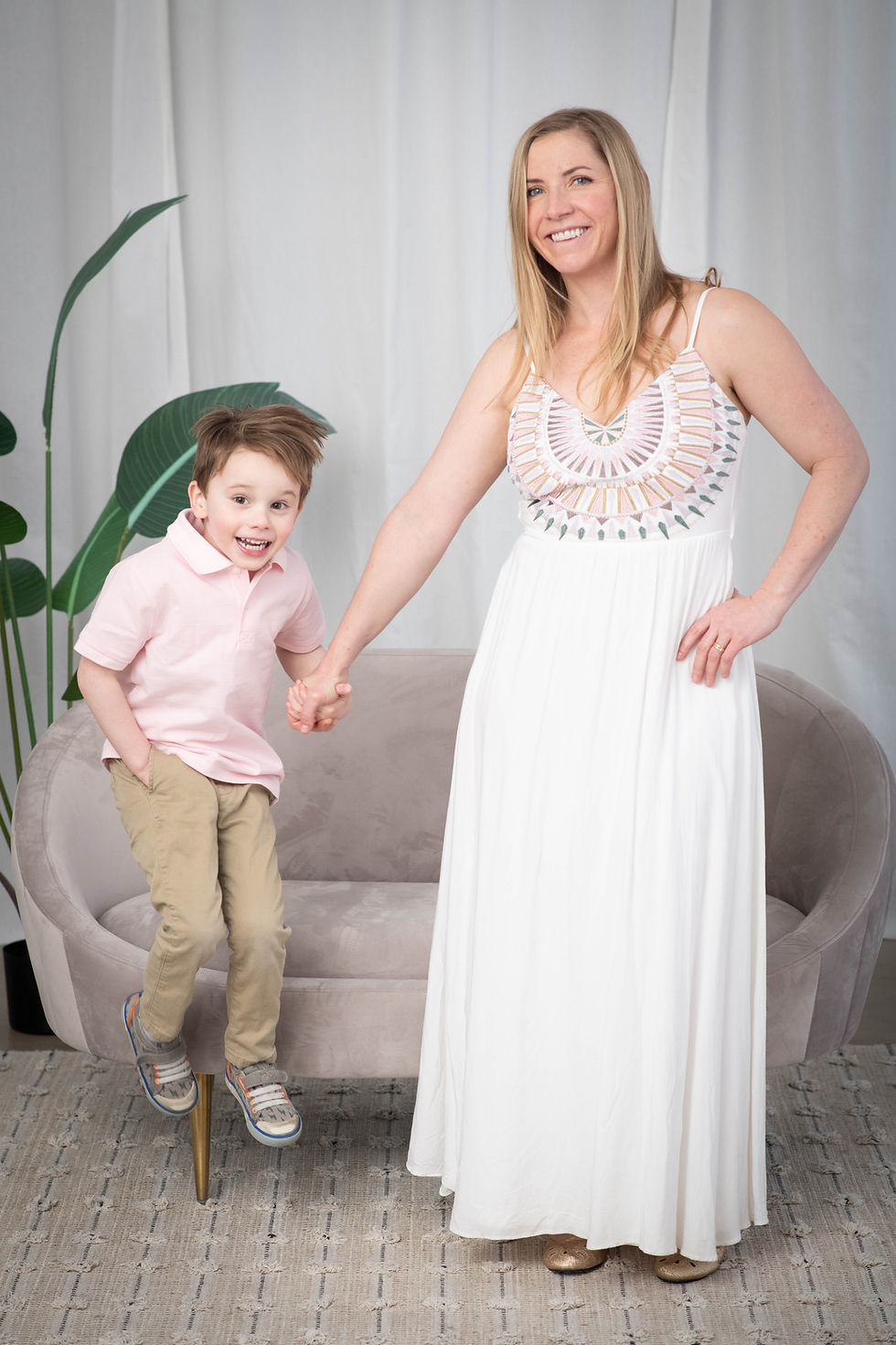 Jane Chevalier smiling and holding hands with her young son, capturing the joy of motherhood and the heart behind Take Care Mama in Highlands Ranch.