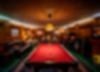 A Game room containing a Pool Table, A fireplaceMultiple Couches, a popcorn machine, a television, and board games