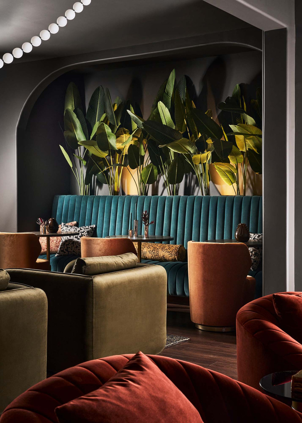 Arched entry framing teal banquette seating and velvet lounge chairs