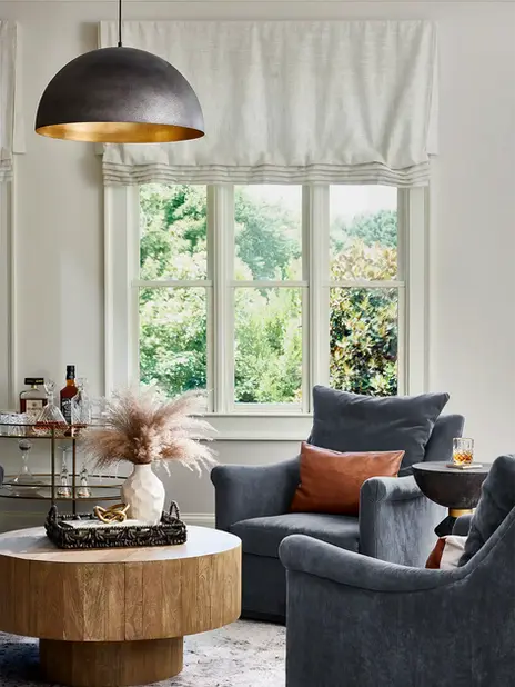 Keeping room and white kitchen designed by HouseLift Design | Atlanta, GA | stone top dining room table wicker dining chairs | blue upholstered swivel armchair | stacked stone fireplace