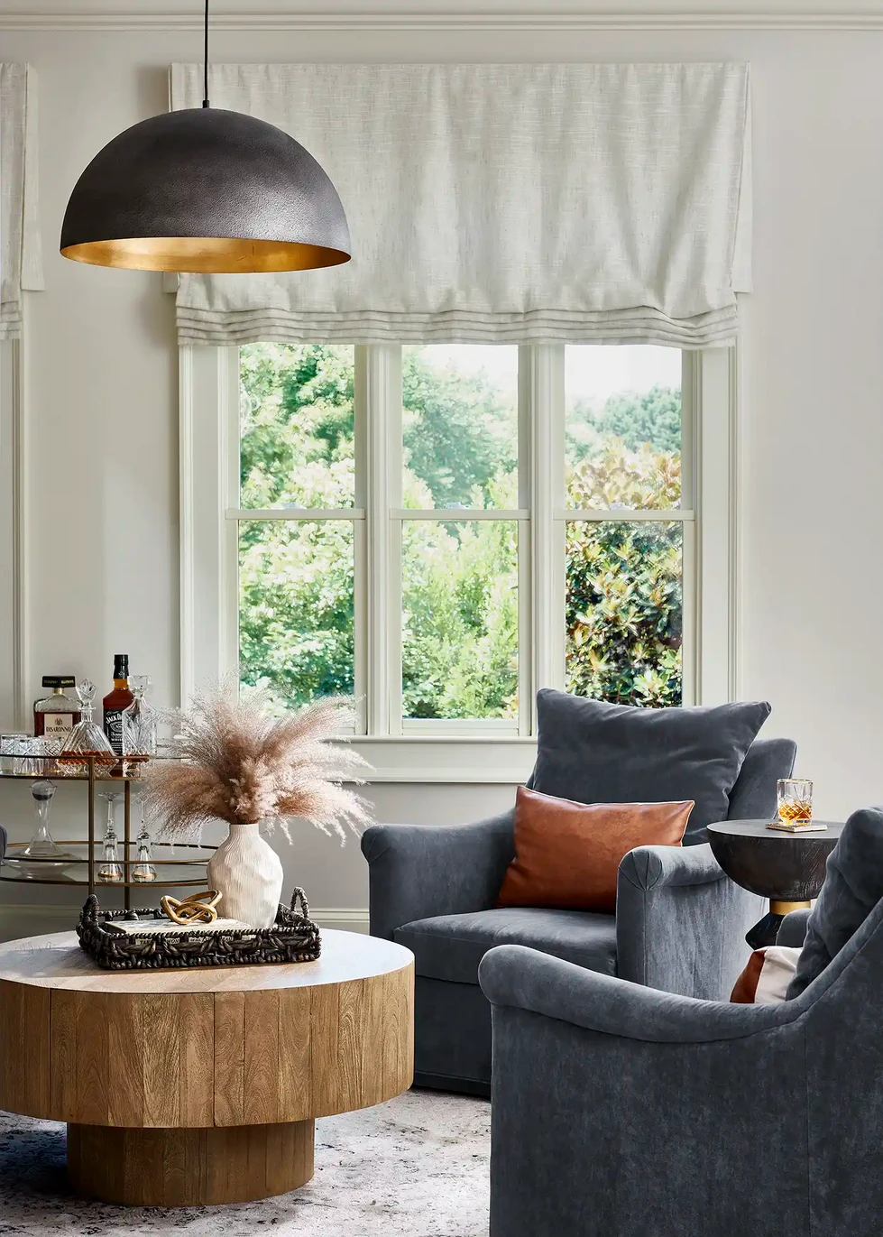 keeping room | sitting room | living room | family room | blue upholstered swivel armchair | blue arm chair | round wood coffee table | brass bar cart | metal dome pendant light | black and brass dome pendant light |