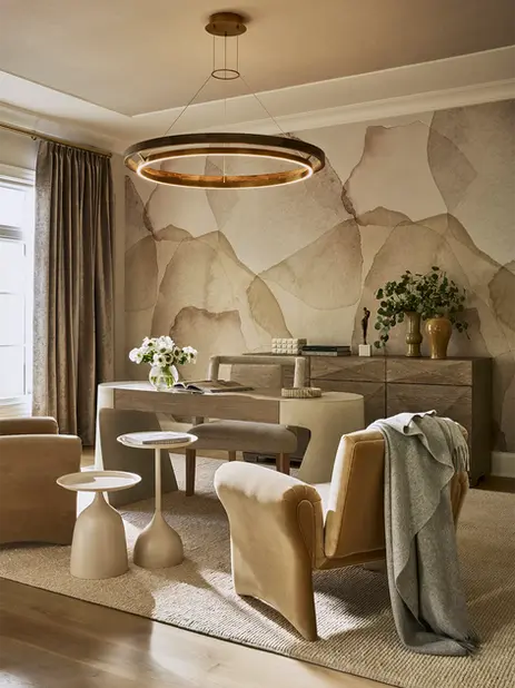 Luxury home office with sculptural desk, custom wall treatment, circular chandelier, neutral palette, and upholstered seating