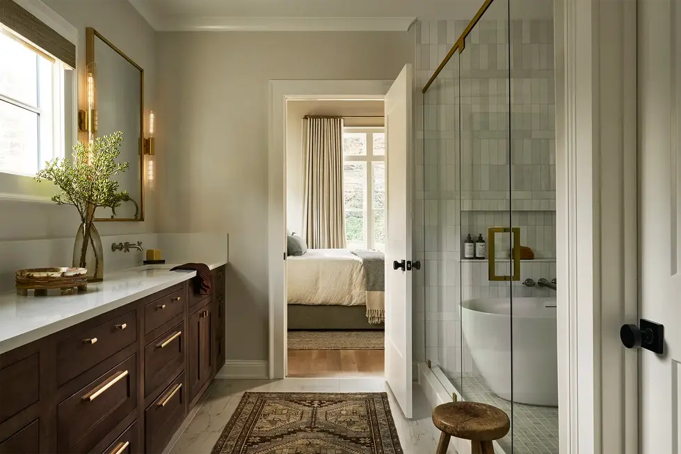 Primary bathroom with wood vanity, glass shower enclosure, tub, and neutral finishes