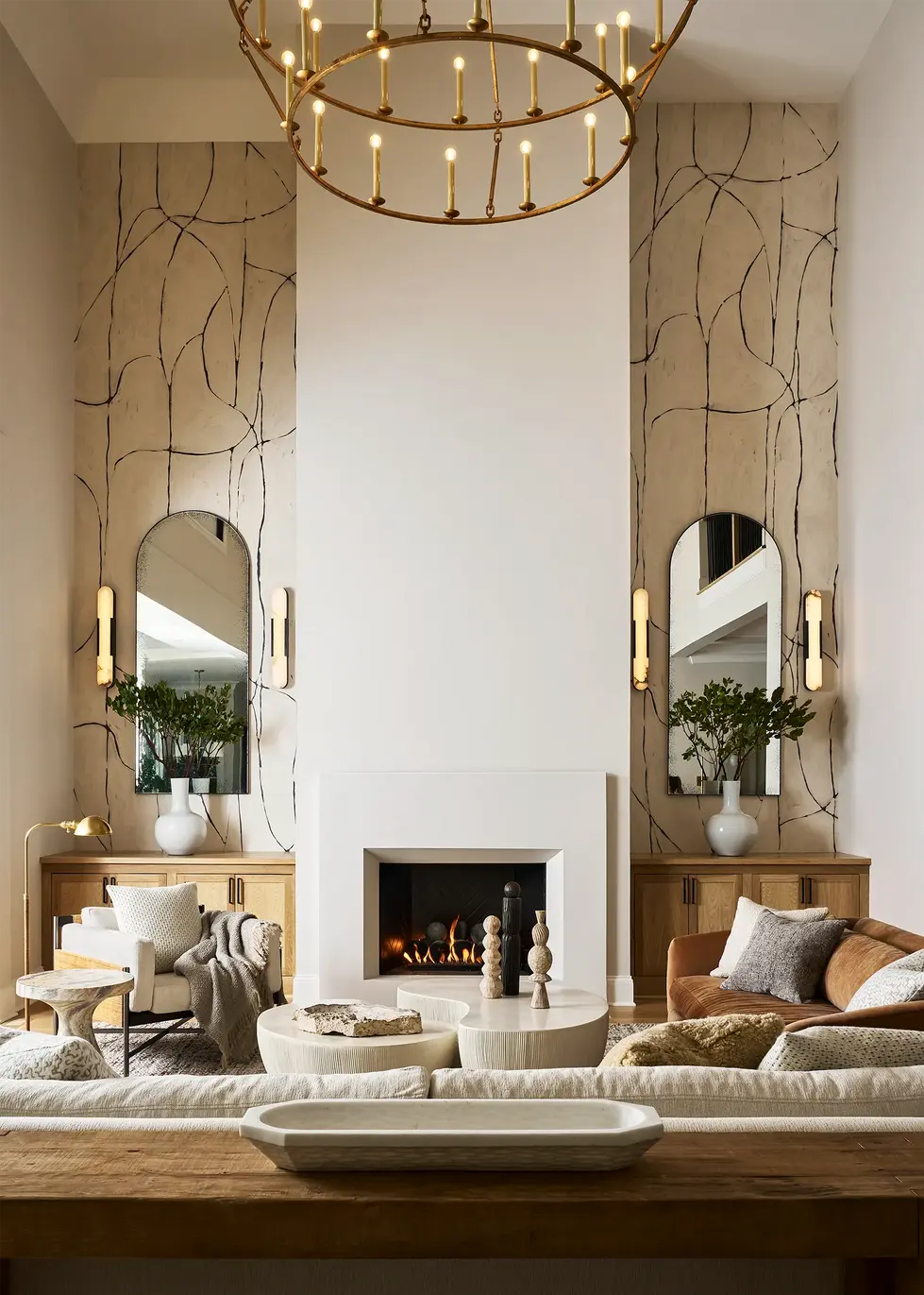 Fireplace wall with symmetrical cabinetry, arched mirrors, and decorative wall finish