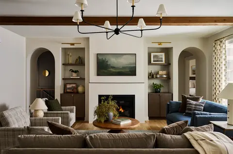 Wide living room with fireplace, built-ins, multiple seating areas, and arched openings