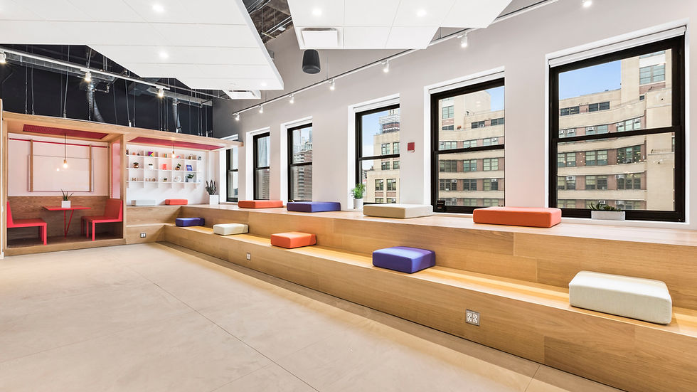 Modern collaborative workspace featuring tiered wooden seating with colorful cushions, large windows providing ample natural light, and a cozy, enclosed booth area for more private interactions-Vaarmor Interior Kanpur