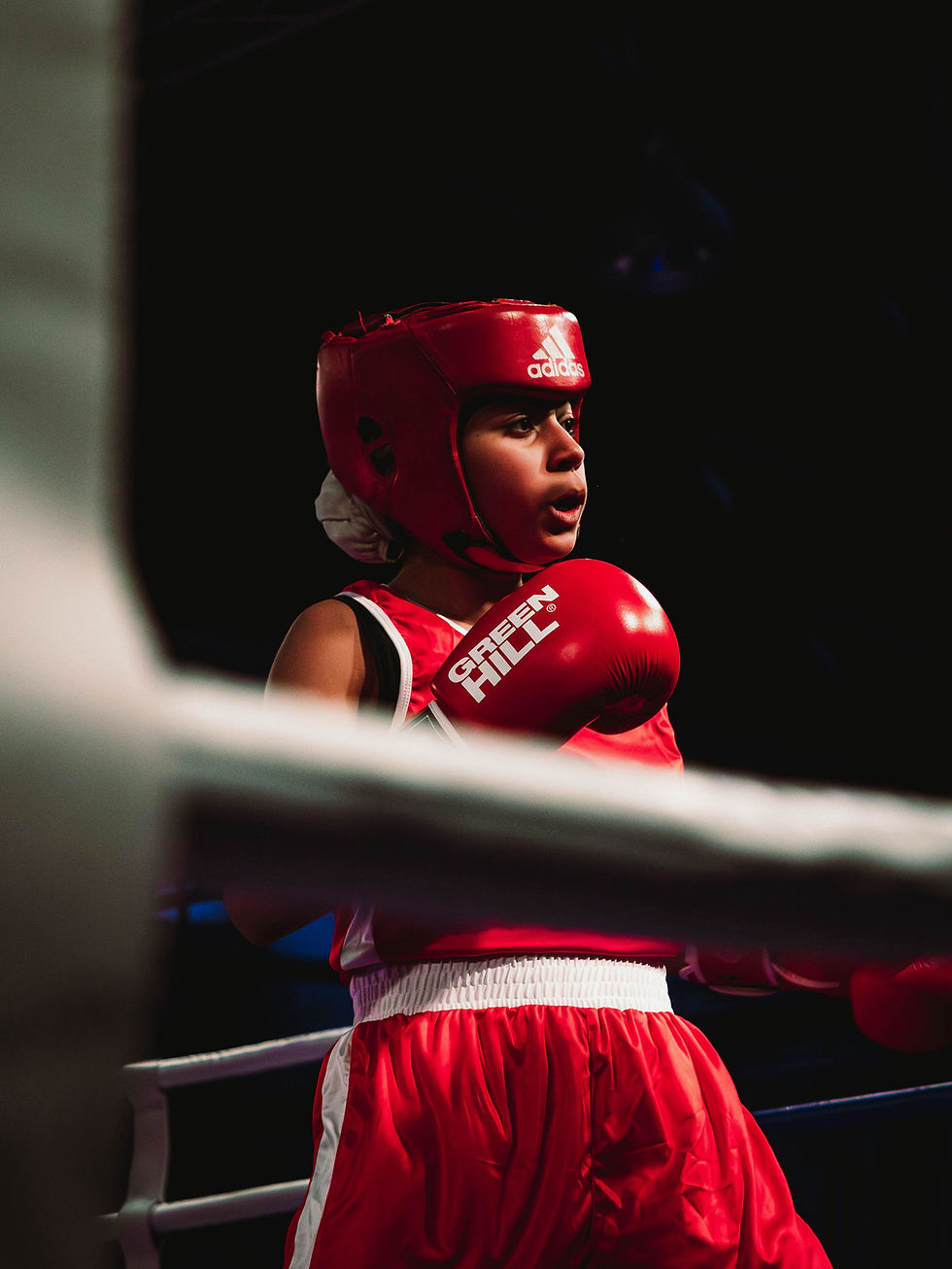 Eye-level view of a boxing ring with vibrant red gloves hanging on the ropes