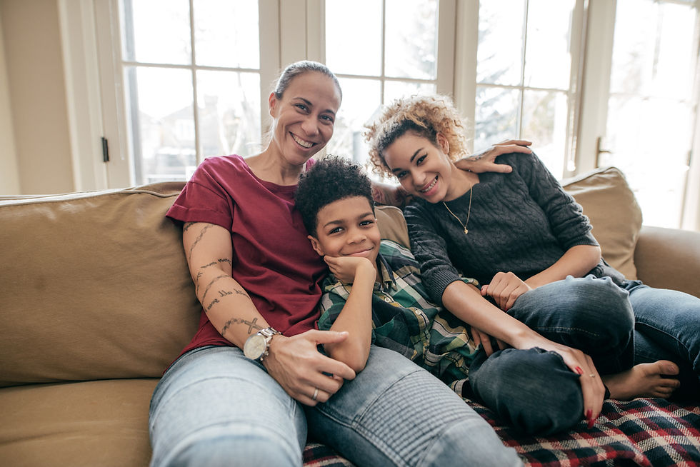 A family of three people sitting on a couch with arms around each other