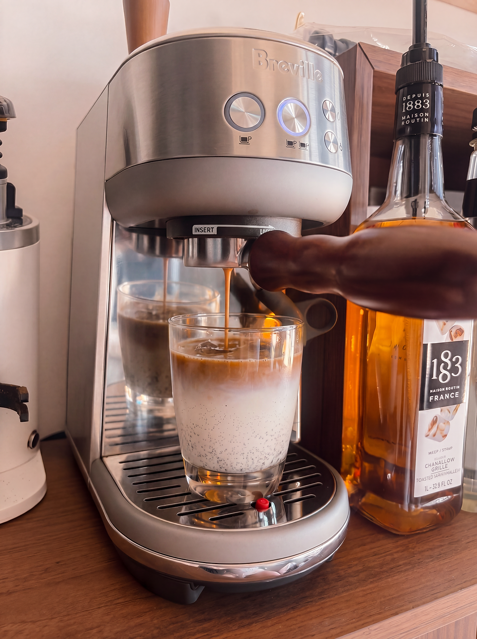 Eye-level view of a Breville Bambino espresso machine on a kitchen counter with a steaming cup of espresso