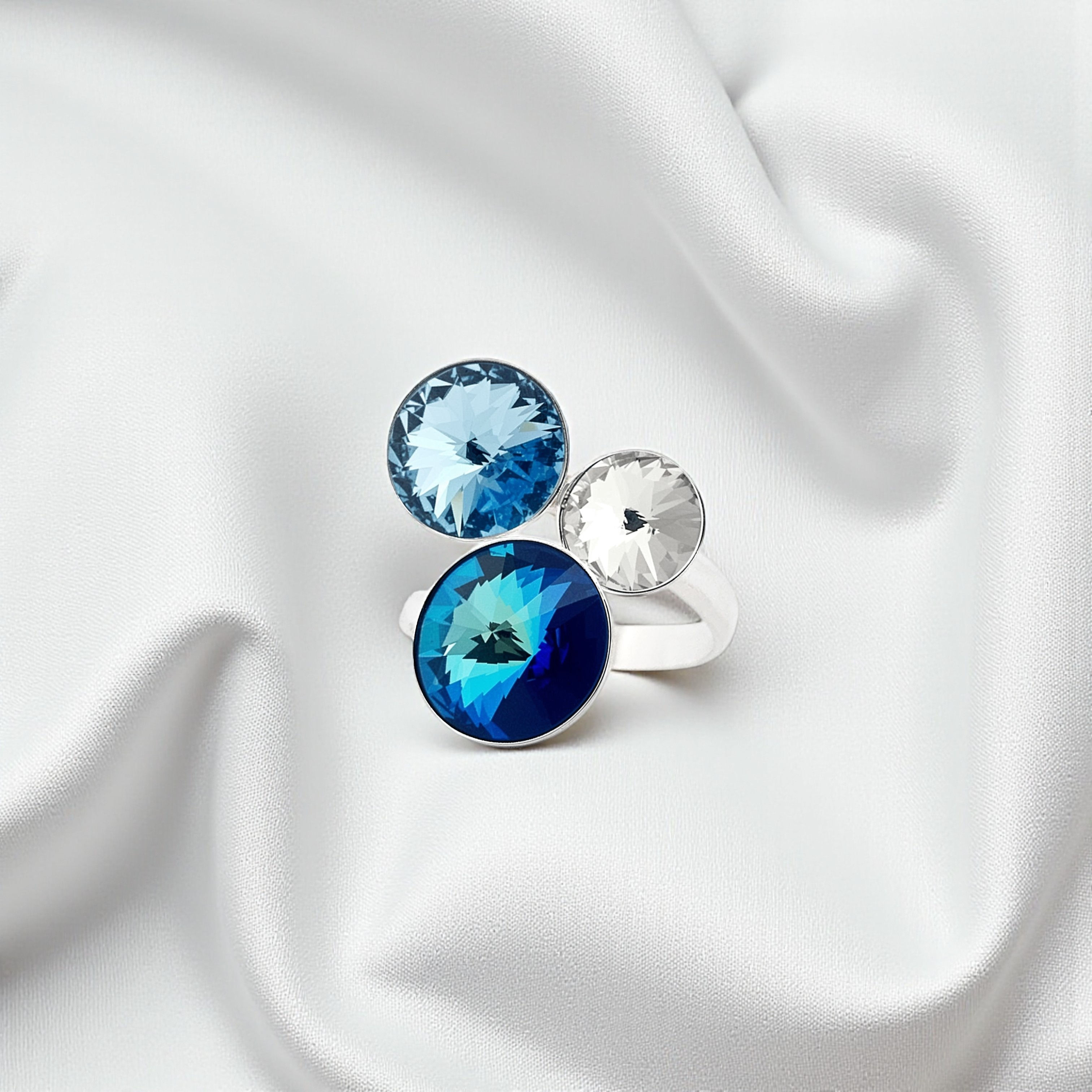 Bague en argent 925 ornée de cristaux Swarovski bermuda blue, aquamarine et crystal, posée sur tissu blanc.