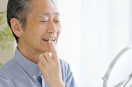 鏡で歯を見るシニア男性