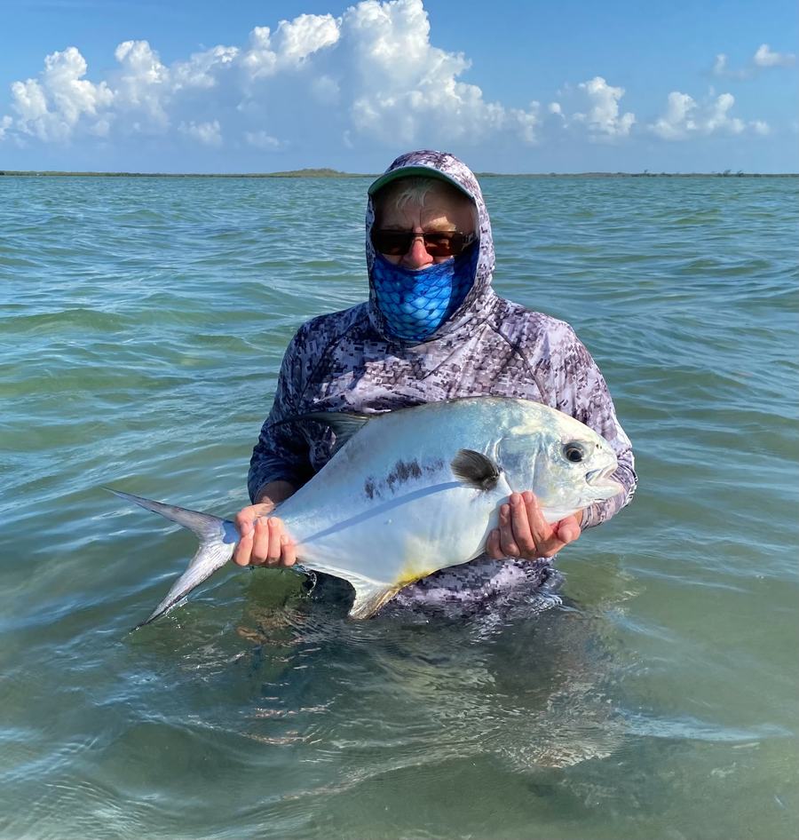 Angler holding a permit, overcast sky