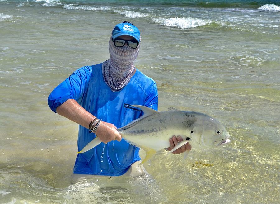 Angler holding a jack crevalle in the surf