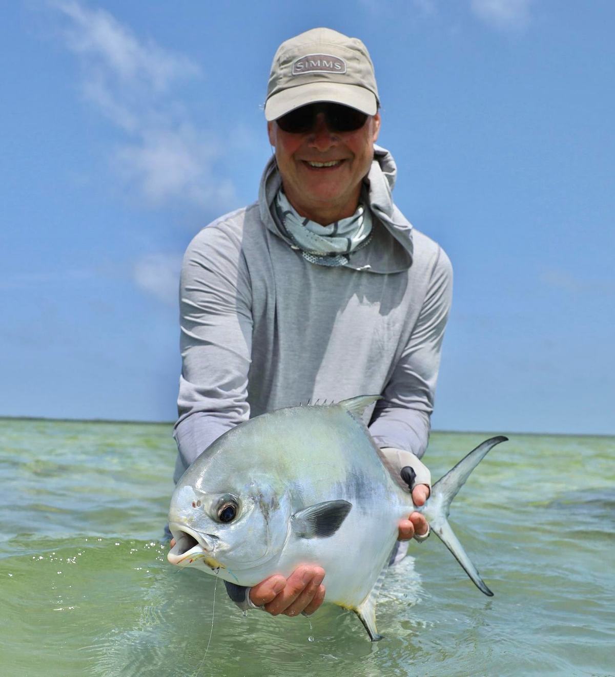 Smiling angler holding a permit on a sunny flat