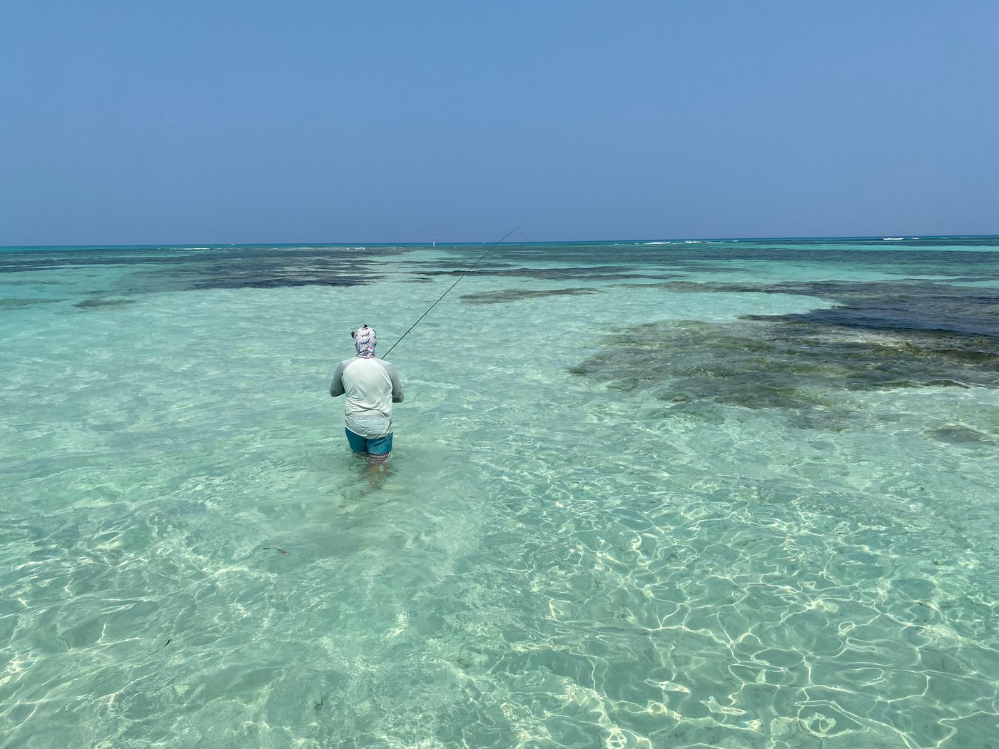 Angler wading a clear turquoise flat near the cayes