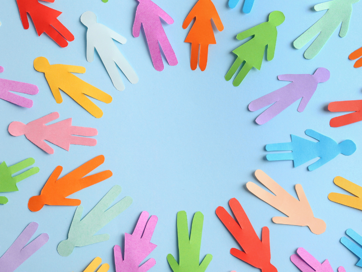 Colorful paper cutout people in a circle around a blank light blue center, suggesting community and teamwork.