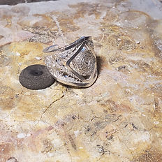 Intricate silver filigree ring on workbench