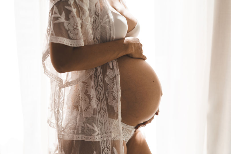 Zwangere vrouw houdt haar zwangere buik vast tijdens een zwangerschapsfotoshoot aan huis in Den Haag.