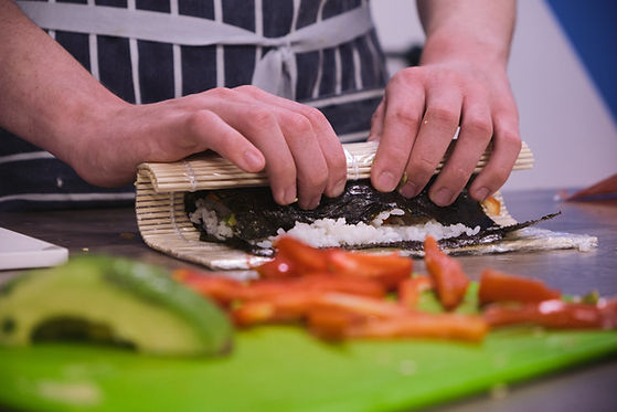 Image of someone hand rolling sushi