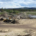 Loader hauling gravel from gravel pit to crusher equipment