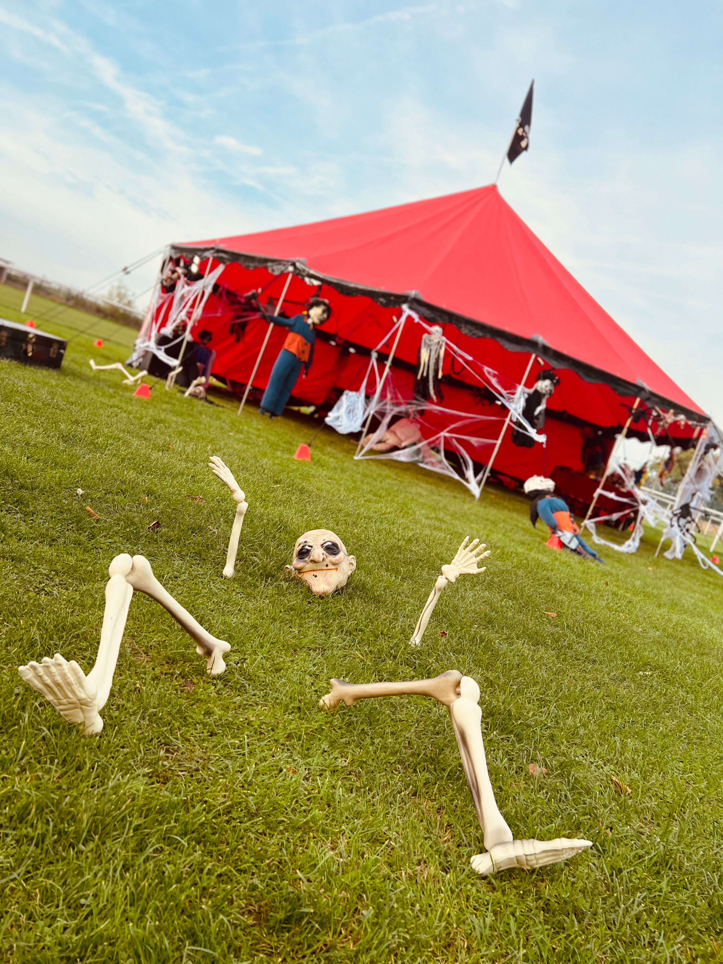 Photo du chapiteau rouge décoré avec de éléments horrifique avec un faux squelette en avant plan