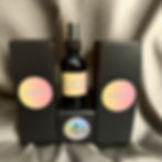 M.Moonchild Scented Creations Candy Room and Linen Spray displayed with sleek black packaging and pastel gradient labels, featuring a soft satin backdrop for a luxurious, handcrafted aesthetic.