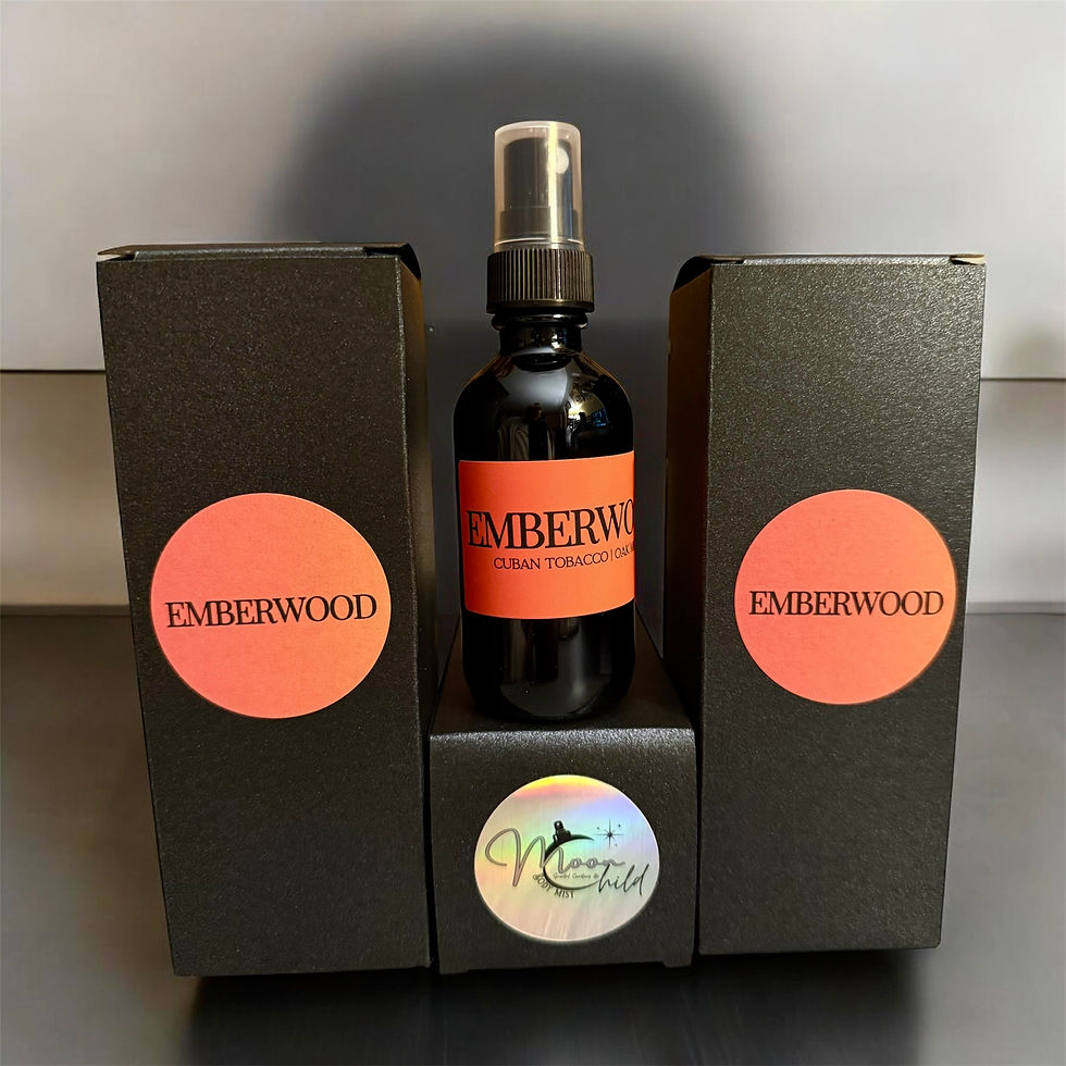 M.Moonchild Scented Creations ‘Emberwood’ room and linen spray in sleek black packaging with bold orange label, displayed against a dark satin background for a warm, luxurious aesthetic.
