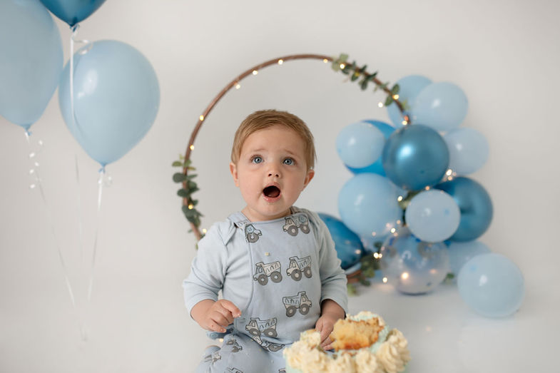 baby-boy-celebrates-turning-one-with-a-blue-themed-cake-smash-photoshoot-with-balloons-at-little-yellow-boots-photography
