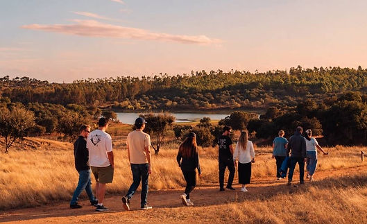Ona (formerly Gitpod) team members walking together along a dirt trail through golden grassland at sunset, with a lake behind.