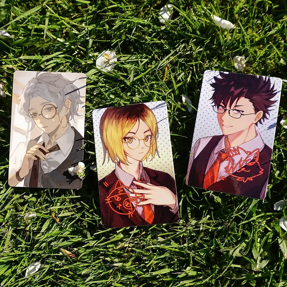Haikyuu photocards laid on grass: Sugawara, Kenma, and Kuroo in suits and glasses