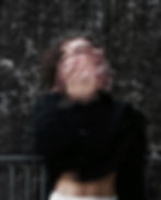 Blurred person covering face, black long sleeve, forest background, monochromatic