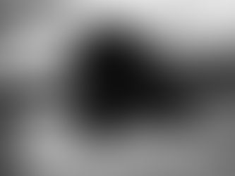 Crno-beli boudoir portret žene koja leži na krevetu, sa bisernim detaljem preko leđa.