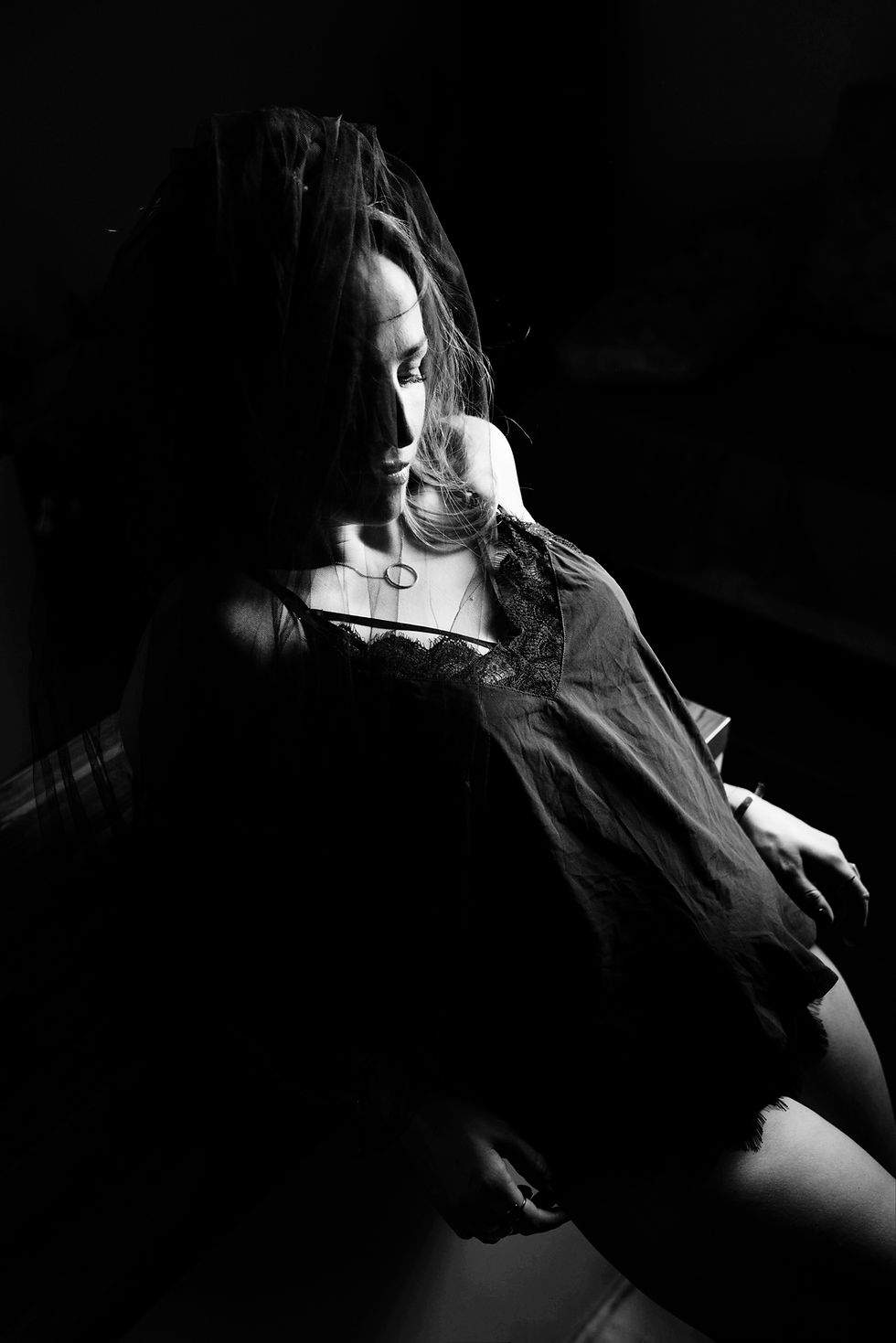 Dramatičan crno-beli boudoir portret žene u tamnoj košulji