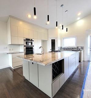 a beautifully transformed kitchen with fresh warm tones on the walls, vaulted ceilings and cabinetry repainted from black to a light off white cream color using a low sheen paint finish to make the space look more open, light and airy.