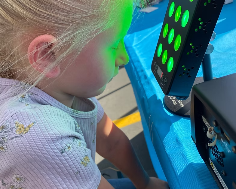 Young girl with eyes closed treats post-concussion headache pain with MyGreen Lamp.