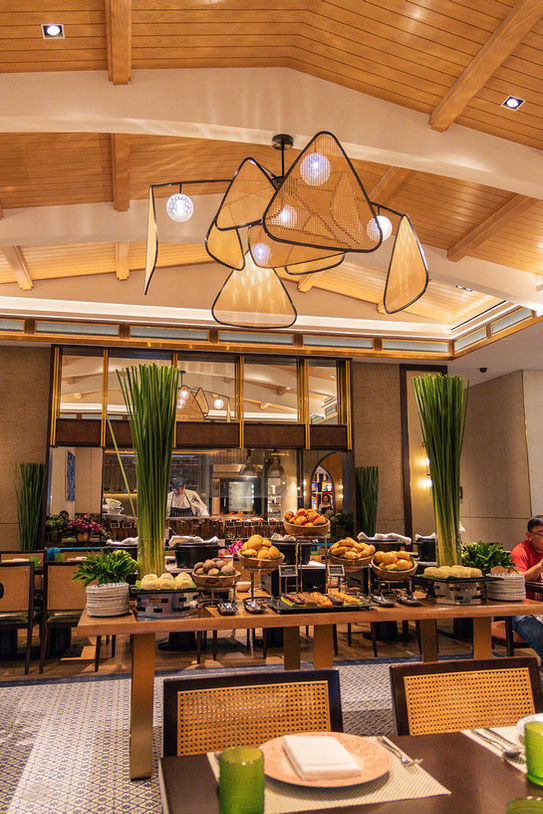 ECDI Signature Project, This image showcases a well-lit restaurant buffet area with an elegant and modern design. The buffet is arranged on a long wooden table under a unique multi-triangle-shaped chandelier, creating an inviting atmosphere.