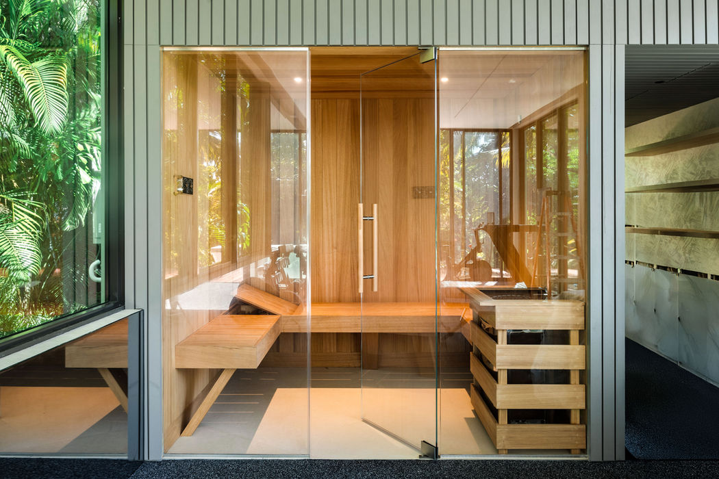 Modern wooden sauna with glass doors and garden view.