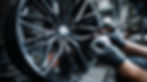 Glossy black alloy wheel being finished with powder coating, highlighting Rhino Coatings’ premium alloy protection services by Foxhills Body Shop.