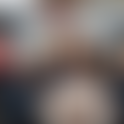Group of smiling people in party hats holding a birthday cake with candles, standing in front of red, white, and blue Ford Transit Vans, celebrating the 60th anniversary of Britain’s most popular van.