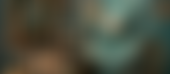 A teal and gold cloth teddy bear sits at an ornate vintage sewing machine surrounded by glowing candles, symbolising the calm and creativity that essential oils for the sewing room can bring.