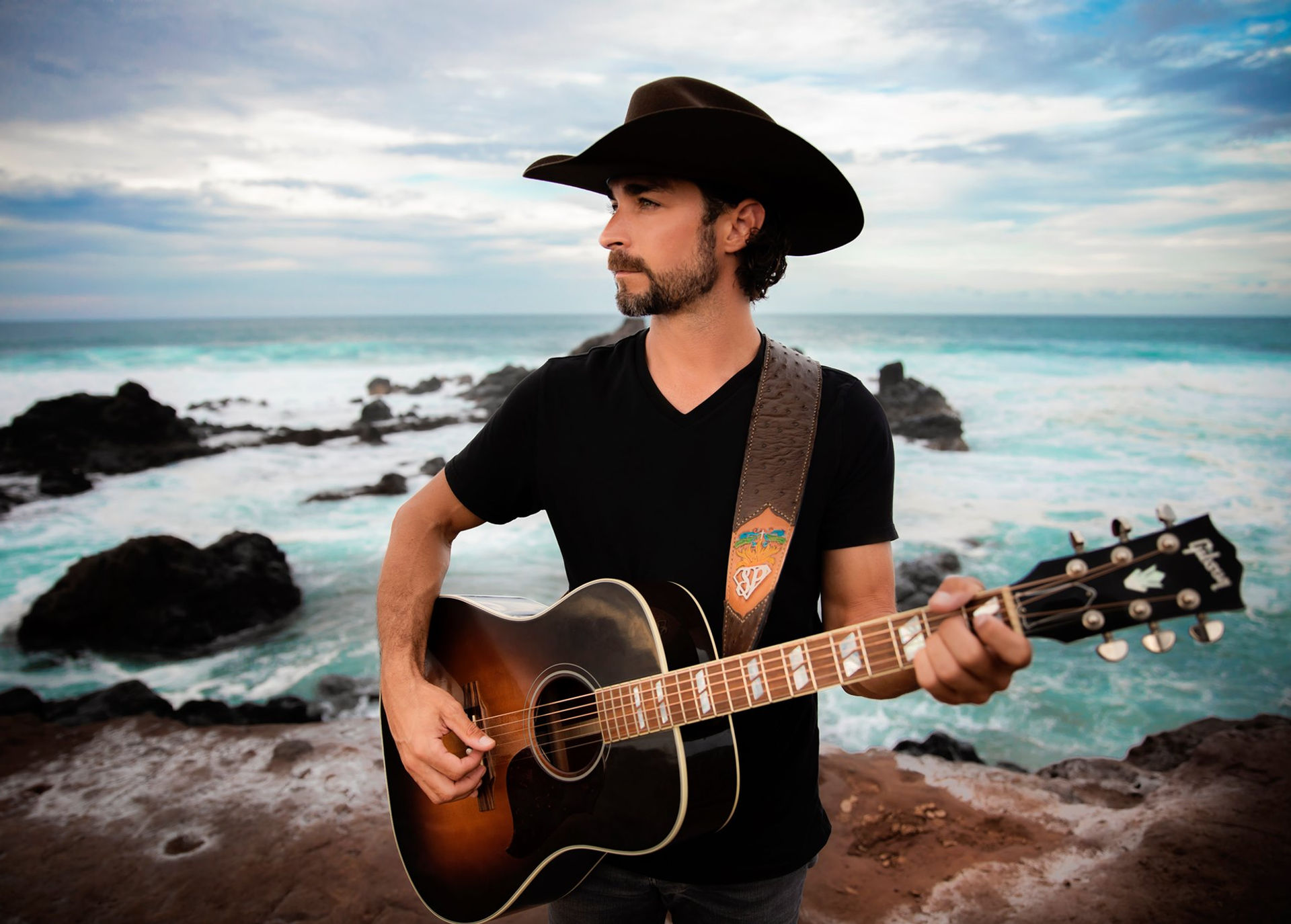 Hawaiian branding shoot for Nashville artist with his guitar on a cliff on Maui