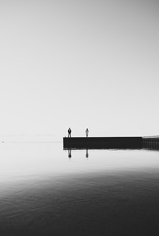 moody cinematic photography of a couple on a pier in the water
