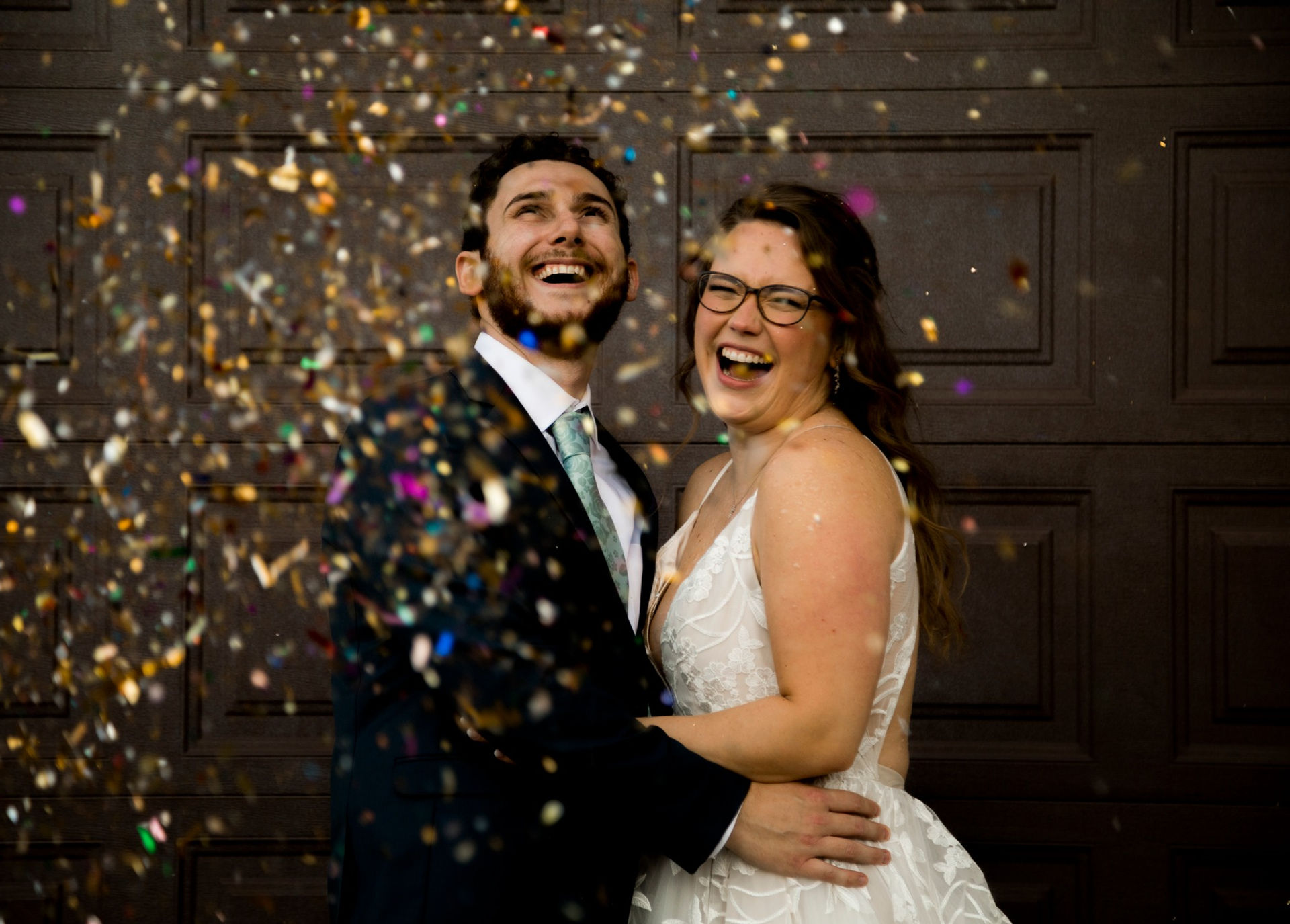 Confetti Pictures at an urban wedding with a rustic backdrop and colorful wedding confetti with bride in glasses