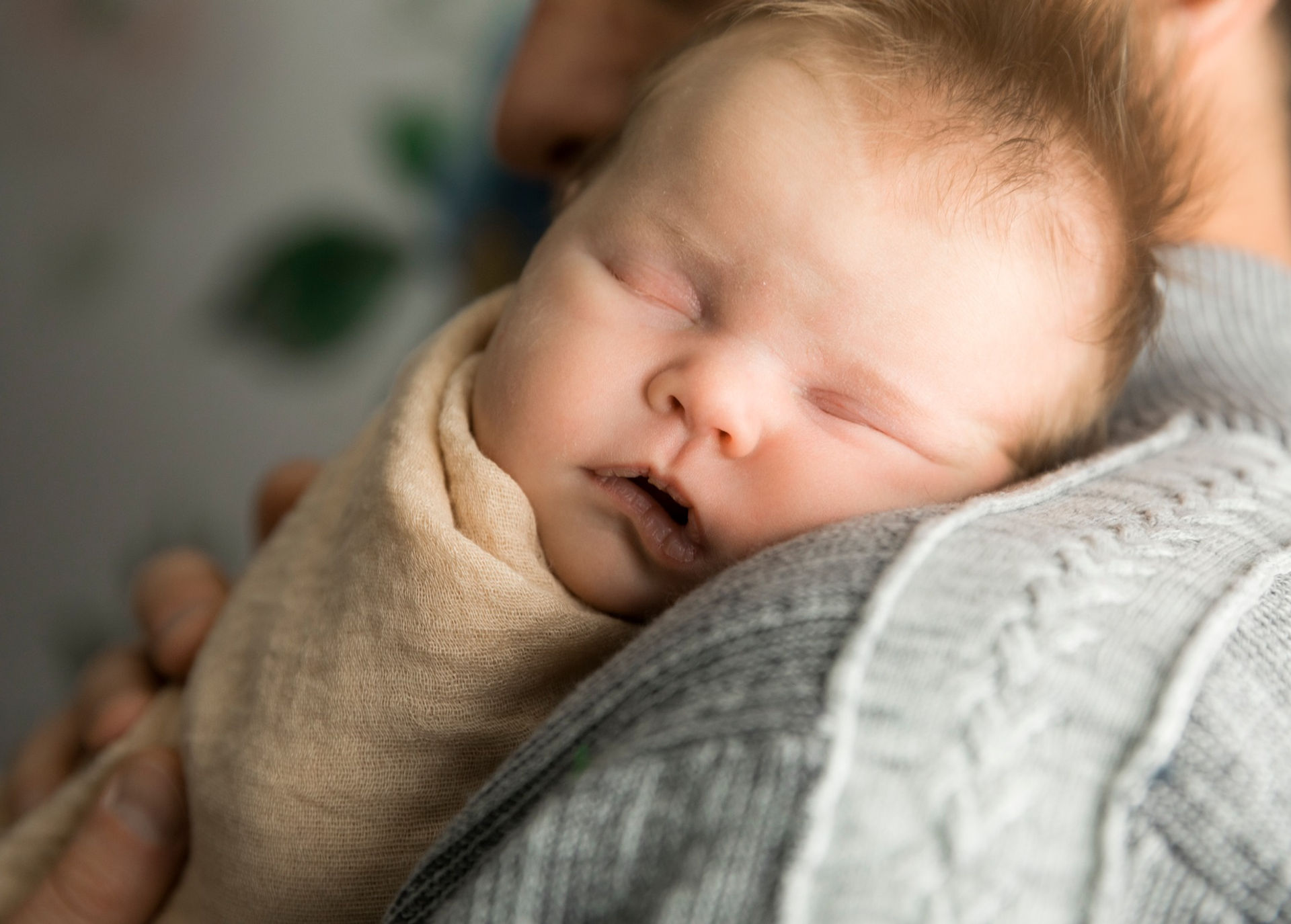A newborn baby snuggles close to her dad in a lifestyle session