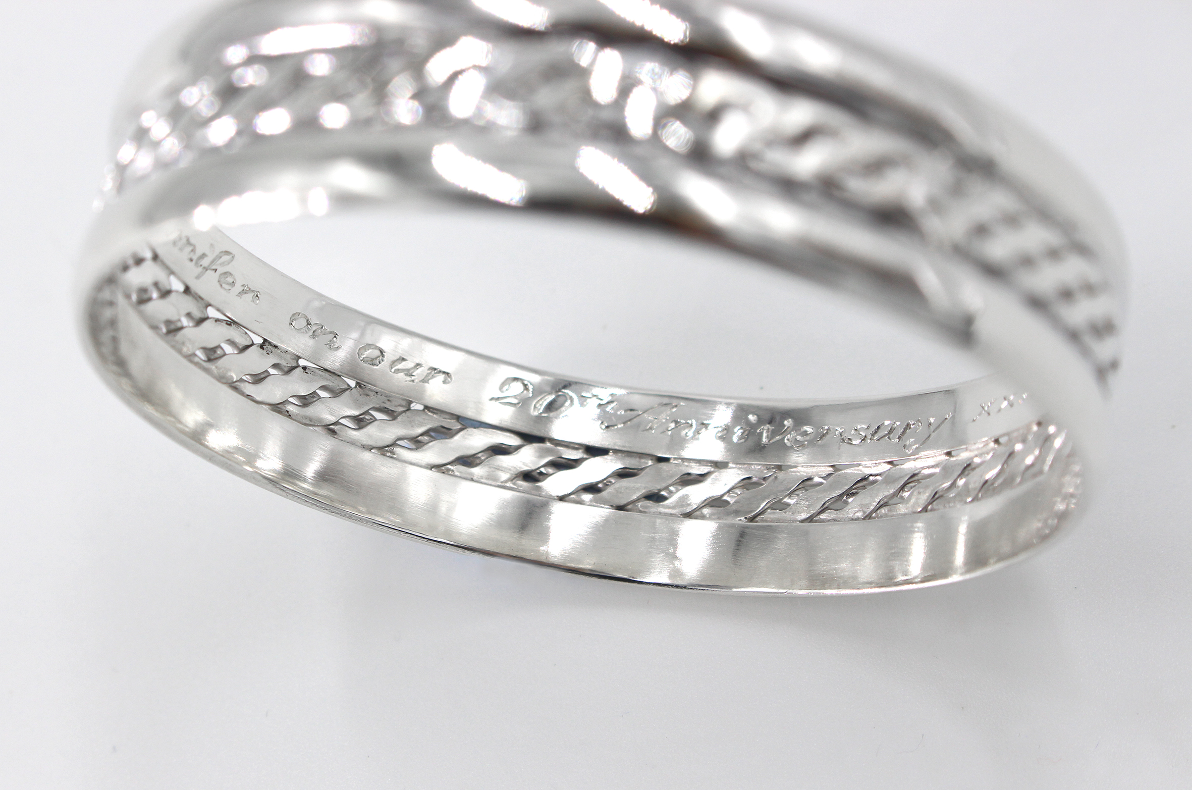 Wide sterling silver bangle with a woven centre and engraved message close up of engraving