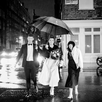 bride and groom walk thrrough the rain after thier wedding in old marylebone town hall
